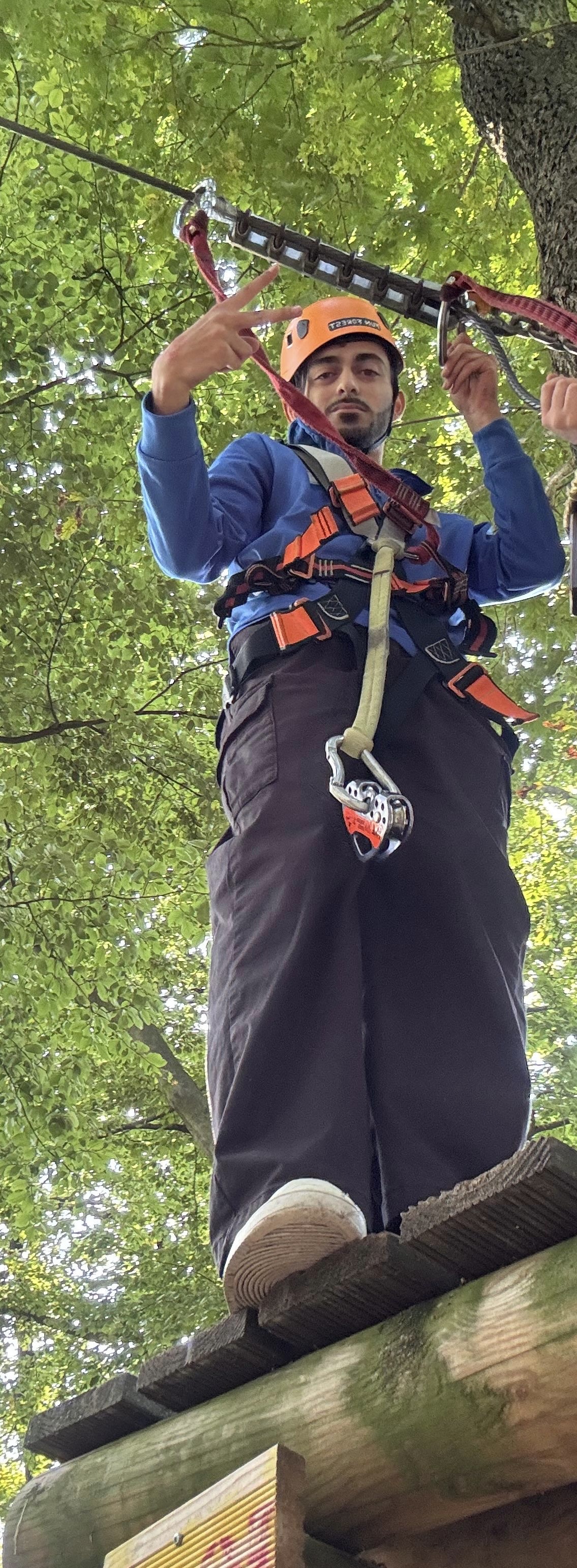 Schüler balanciert gesichert auf einem Holzbalken im Hochseilgarten